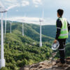 Man in high visibility vest looking at wind farm