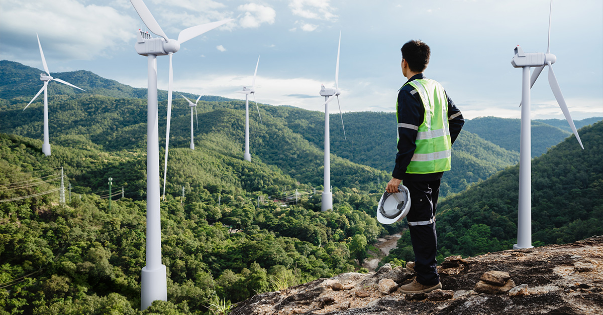 Man in high visibility vest looking at wind farm